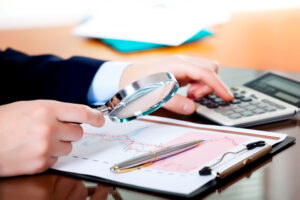 Mano con lupa sobre auditoria de estados financieros